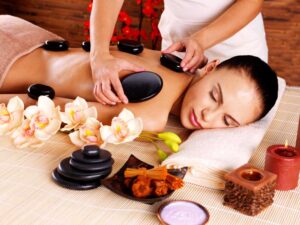 Adult woman having hot stone massage in spa salon.